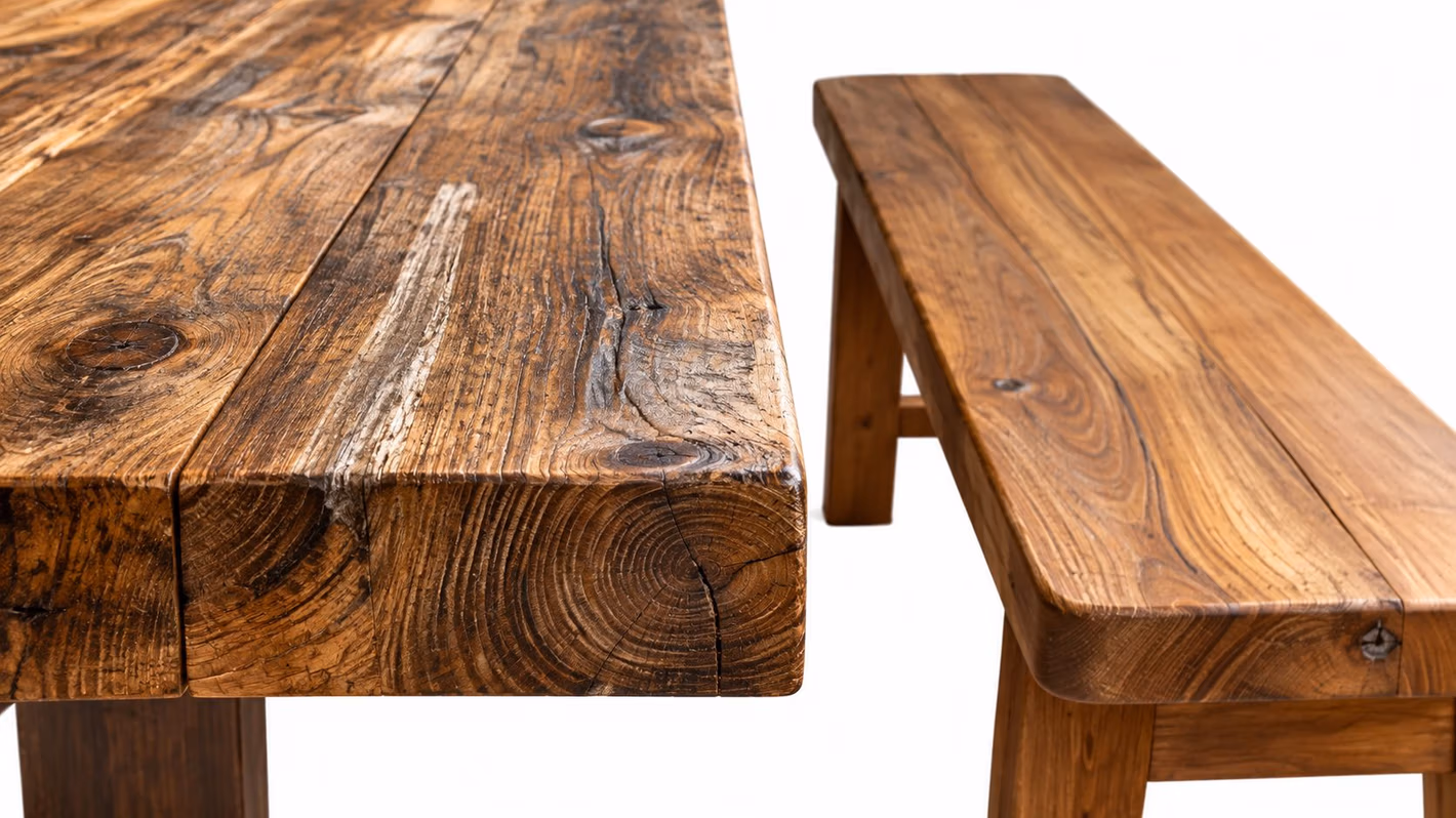 A close-up view of a rustic wooden dining table and bench set with visible wood grain patterns.